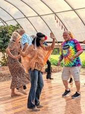 FP1 Maria McDade, center, of Newton and Jeff Sisco, right, of Branchville on the dance floor during a Flower Power ’60s Dance on July 27 at Sunset View Farm in Lafayette. (Photos by Maria Kovic)