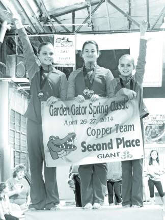 Representing the Copper Gators as they receive their teams' banner are Audrey Biss, Morgynn Witt and Reese Abrams.