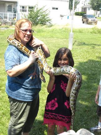 Alisha Anjum, 8, of Hardyston, gets to hold up one section of the Burmese python.