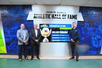 Former Sussex County Community College athletic director John Kuntz, center, stands in front of the new John M. Kuntz Athletic Hall of Fame Wall. With him are current athletic director and associate dean of students Todd Poltersdorf, left, and the college’s interim president, Cory Homer. (Photo by George Leroy Hunter)