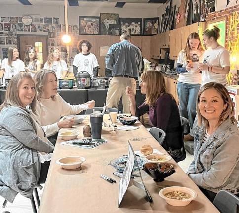 EB2 Staff members, from left, MaryRose Potanka, Lauren Ayers, Cathy Astor and Tricia Traglia eat soup and bread at the fundraiser. At back from left, students Adrianna Romeo, Natlie Wynn, Charlotte Flatt and Sammy Barbato help Superintendent Dave Carr decide which soup to try. At right students Des Cerracchio and Carly Trovato photograph the event.