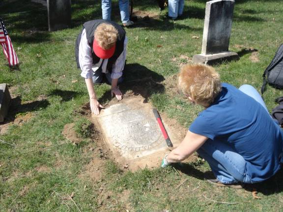 DAR members Nancy Malone, left, and Lisa Permunian carefully work to uncover a grave marker that has been buried over time. Photos by Scott Baker