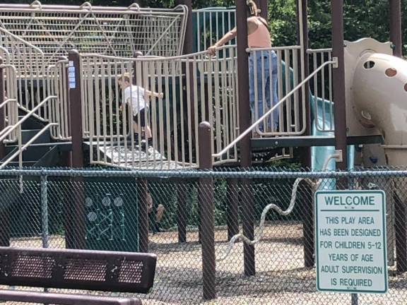 A woman watches her son play at the New Creative Playground, behind Bearfort Shopping Village in West Milford, earlier this month. (Photo by Kathy Shwiff)