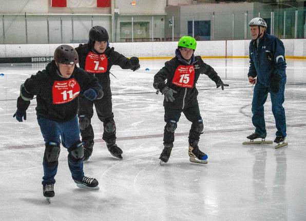 Volunteer Al Harding watches speed skaters, from left, Joseph Pilchuk, Salvatore Luppino and James Smith.