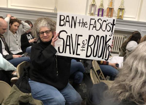 Simonetta Jean of Sparta holds up a sign at the Board of Education meeting Thursday, Feb. 23.