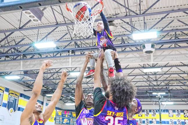 HW1 Several Harlem Wizards help Owen Magath, 4, of Jefferson dunk the ball to score the final point of a fundraising game Feb. 7 at Jefferson Township High School. (Photo by George Leroy Hunter)