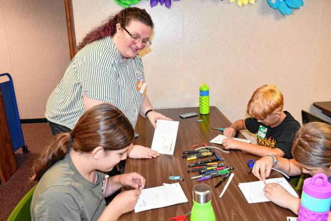 Librarian Cara McLaughlin watches children work on a STEM project Wednesday, July 17 at the Franklin branch of the Sussex County Library System. Among the projects were making a light-up nametag, firefly and magic wand and creating a mechanical grabby arm to learn the basics of low-tech robotics. (Photo by Maria Kovic)