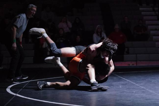 A wrestling official keeps close watch on the action on the mat.