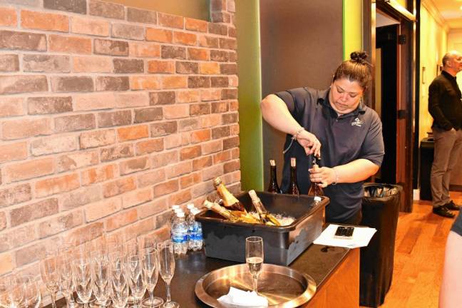 A staff member opens a bottle of wine.