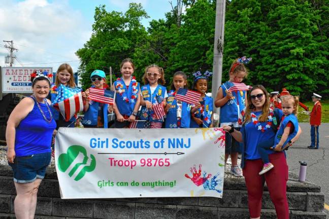 Members of Girl Scouts Troop 98765 pose with their banner.