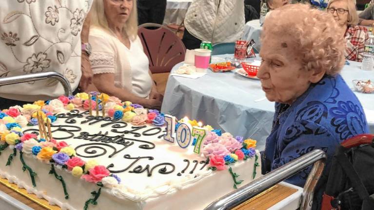Jennie Switzer, 107, of Newton blows out the candles on her birthday cake Saturday, May 18. The cake, with 107 roses, was made by Chad Gasiorek of the Sussex County Technical School bakery. (Photos by Kathy Shwiff)