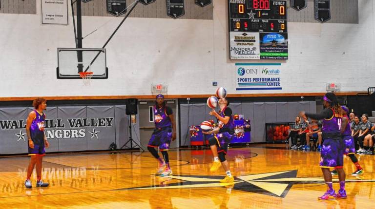 A member of the Harlem Wizards juggles three basketballs.